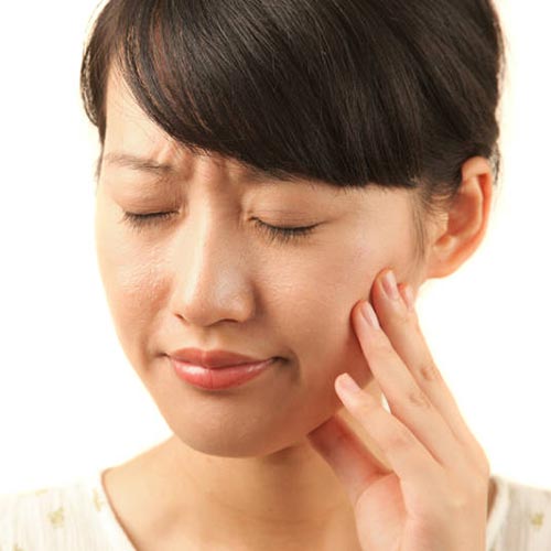 woman holding her cheek due to tooth pain